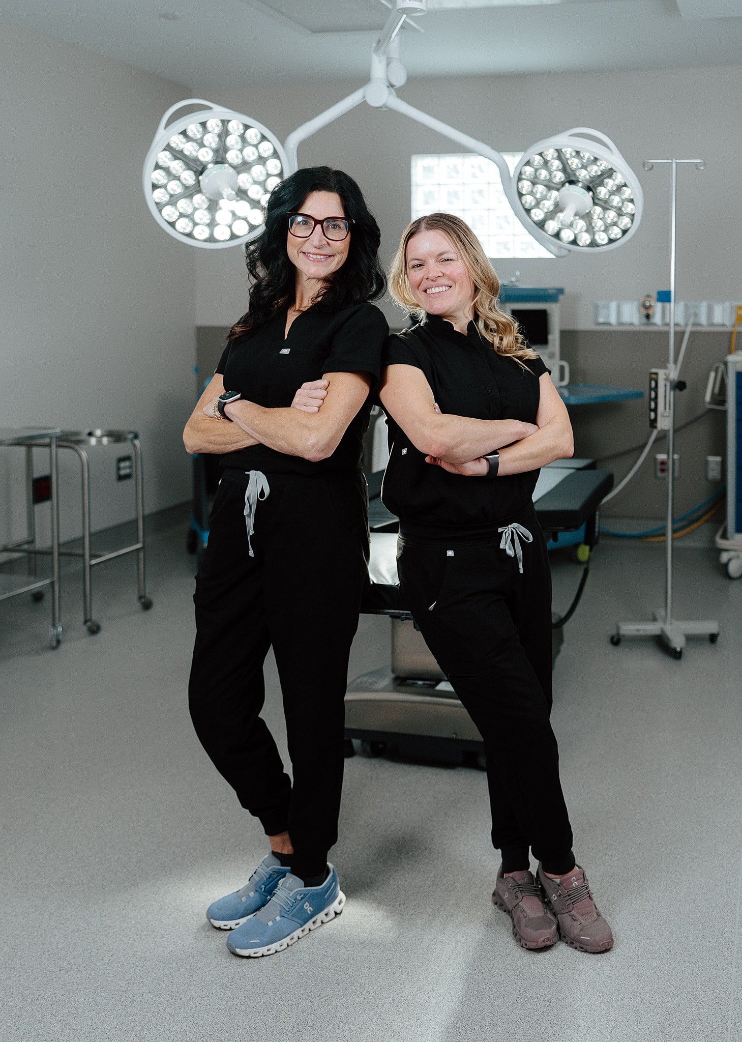 Two women in scrubs, standing confidently in a clinic.